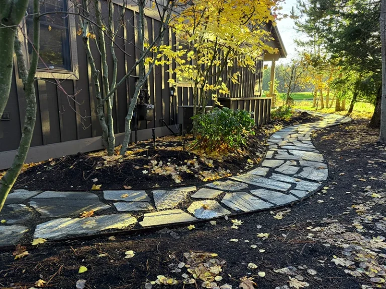 Curved flagstone pathway with fresh mulch and landscape edging along a residential home.